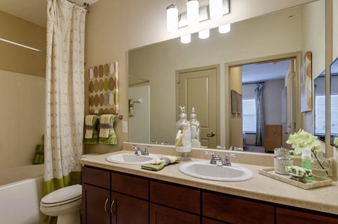 Model bathroom with double vanity, double storage underneath sinks, and large mirror at Ashley Auburn Pointe in Atlanta, GA
